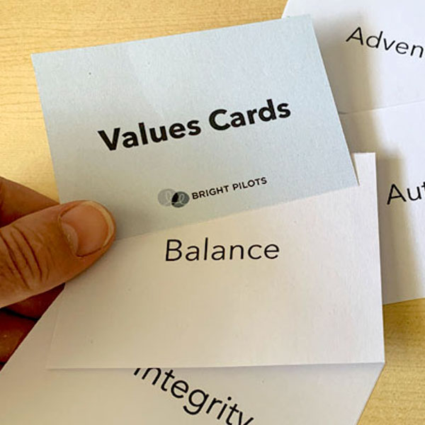 A photo of a hand holding one of several cards with various values printed on them